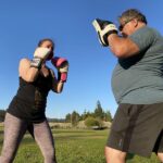 Photo showing happy people participating in Trainer Dave's kickboxing class, outdoors.